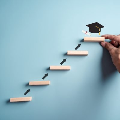 Steps of education leading to success goal. Taking strategic steps towards graduation. Career path and first for business, Graduation achievement goals concept. Graduation cap on wooden block.